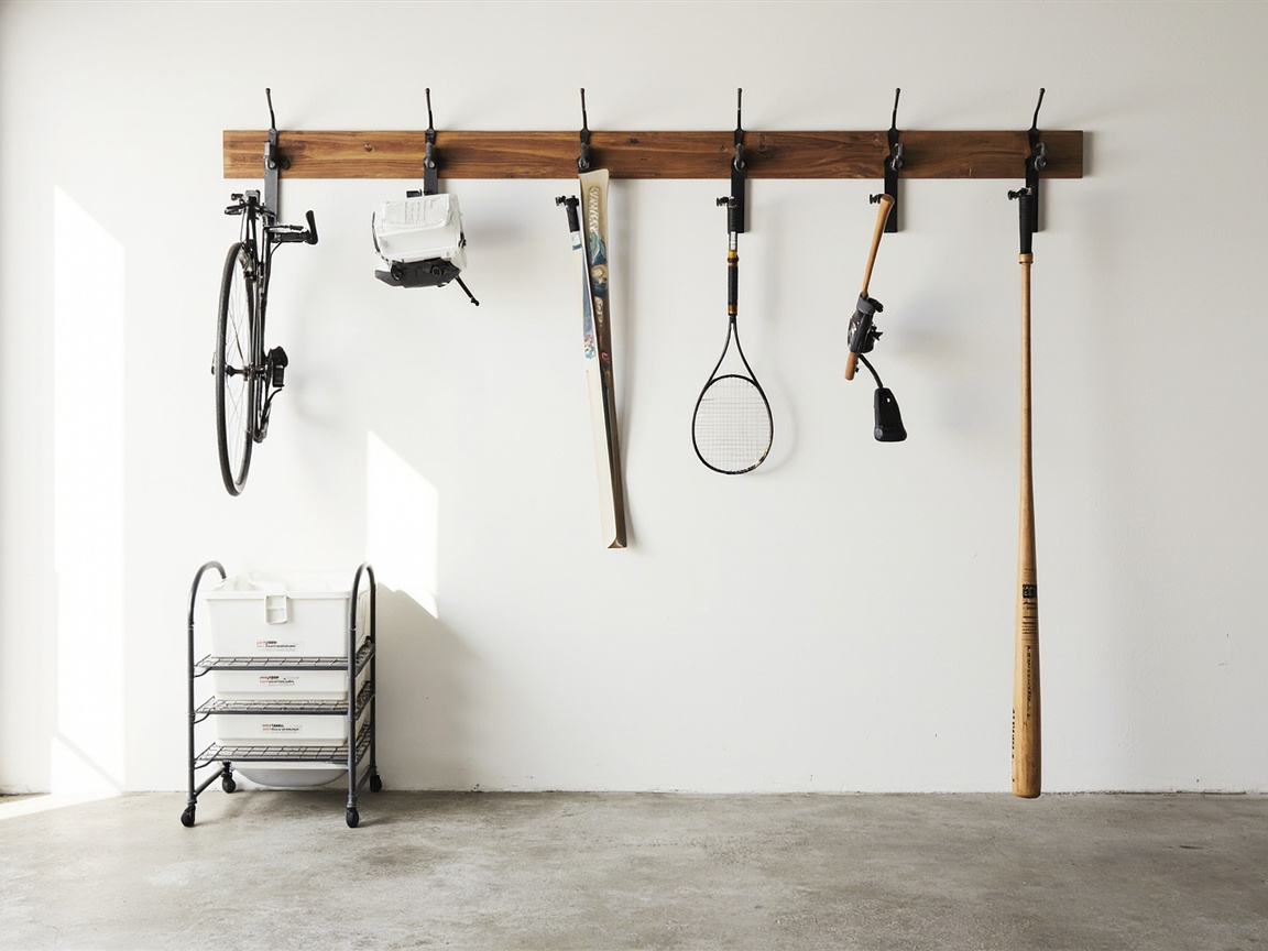 Garage wall hooks holding bikes skis fishing rods and tennis rackets vertically