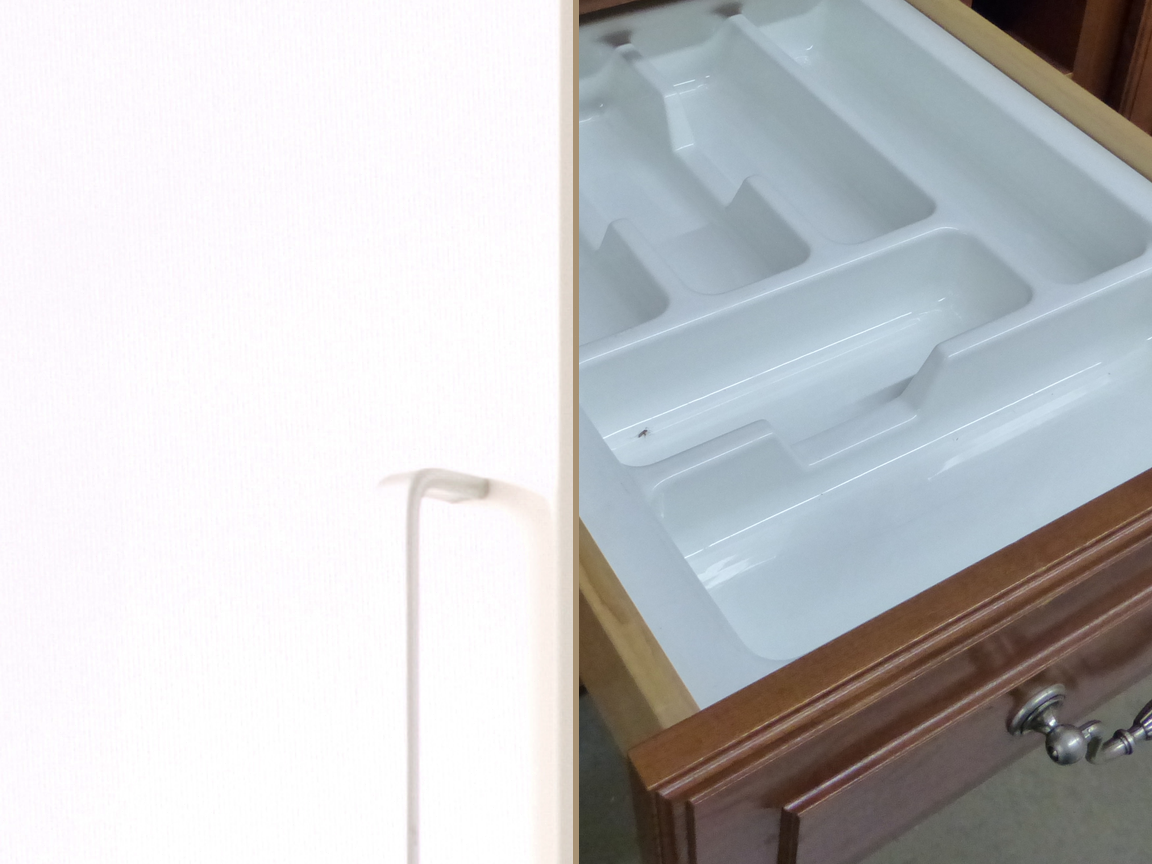 Swung-open kitchen cabinet door inside face next to an open wood drawer with a divided utensil tray